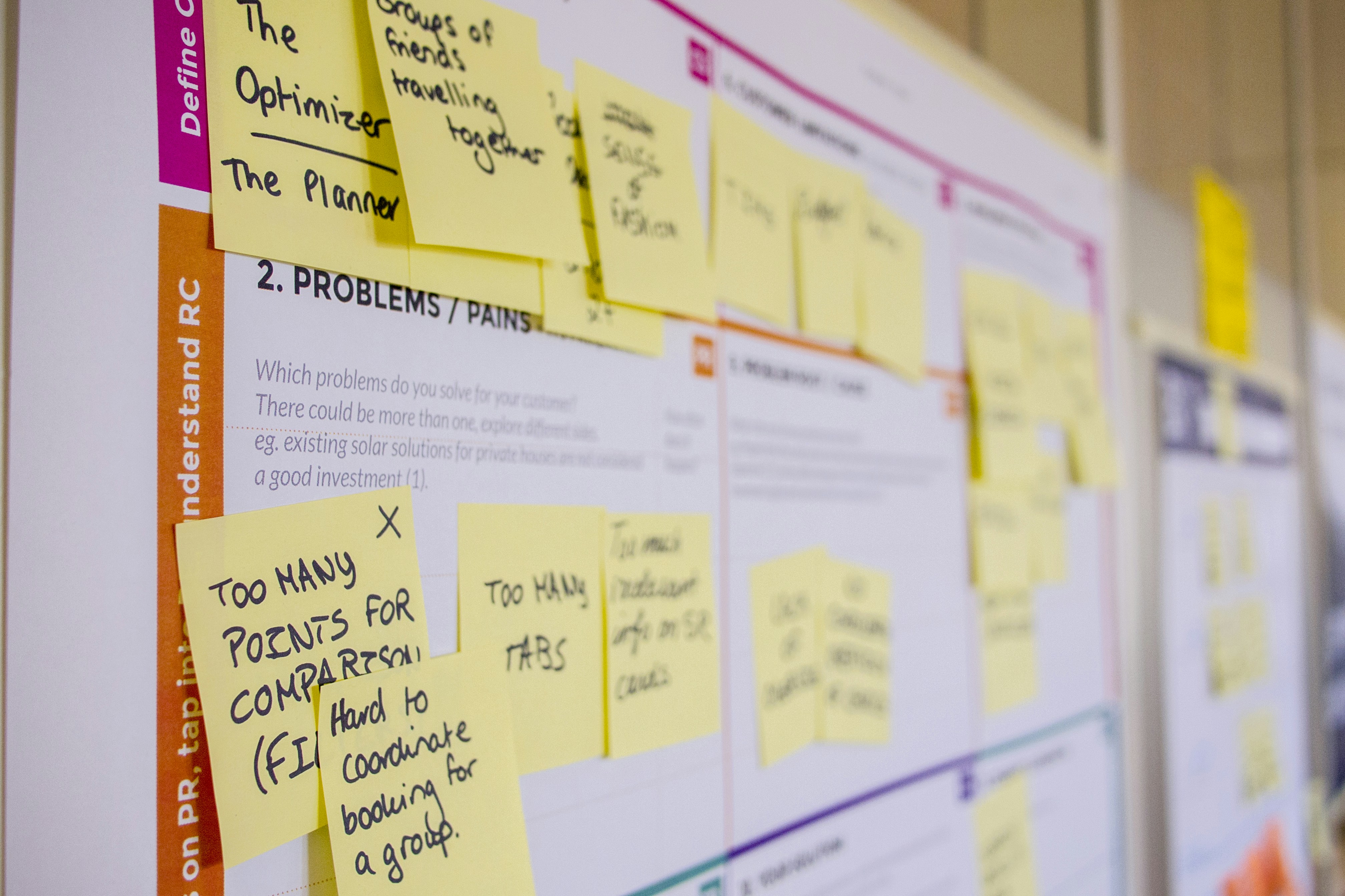 A brainstorming or problem-solving board filled with sticky notes, each featuring handwritten ideas, placed in a brightly lit workspace.